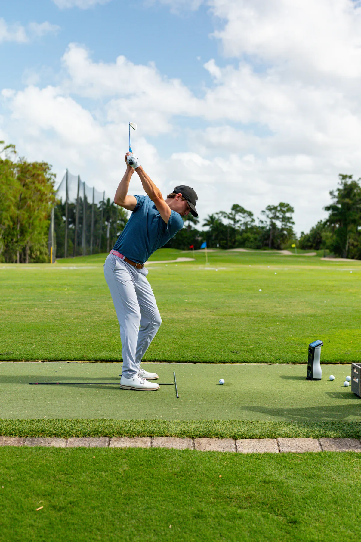Coach Ryan Hogan mid-backswing on the practice tee