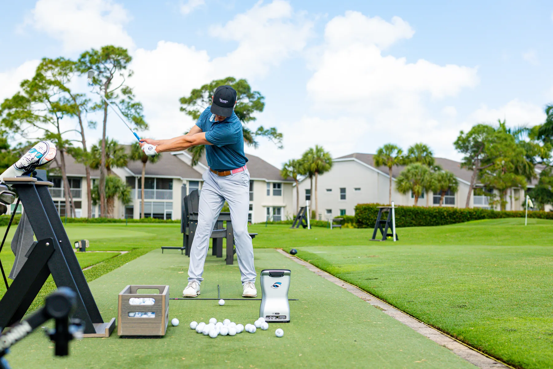 Ryan Hogan mid-swing with launch monitor in foreground at Redline Golf Academy